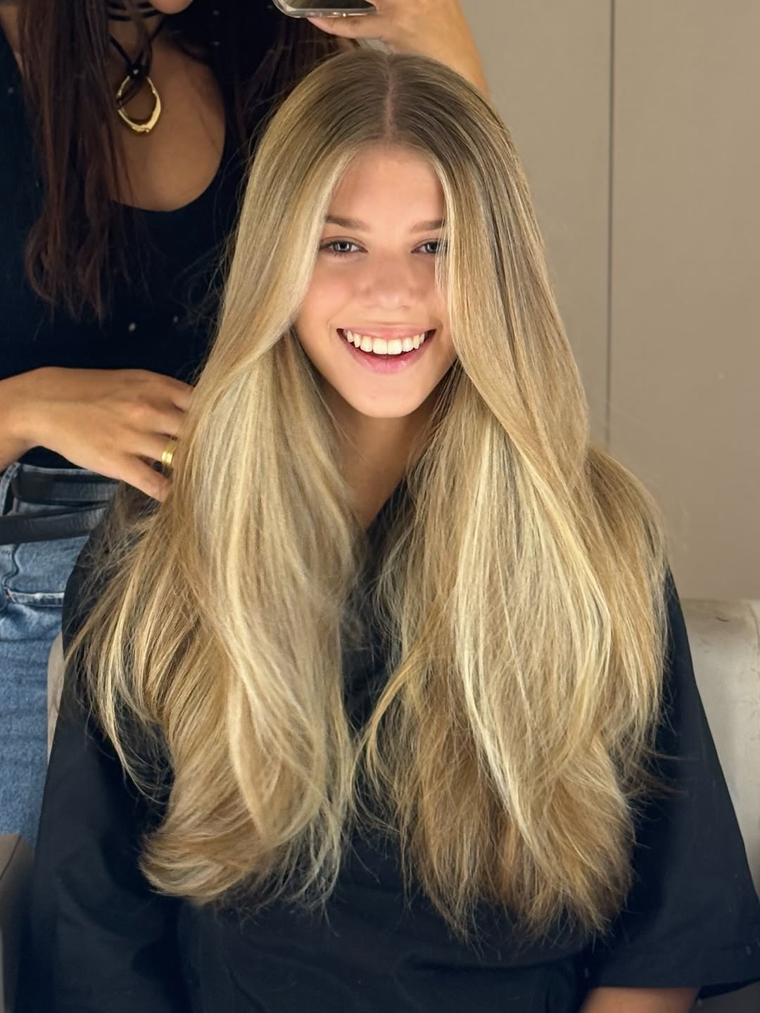 Cliente da Lívia Calmon Beauty com loiro longo iluminado, sorrindo no salão